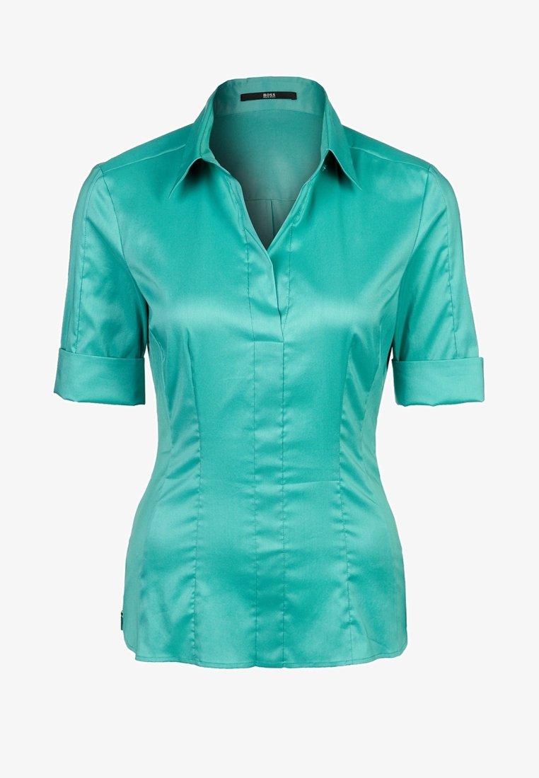 Blouse en satin bleu sarcelle à manches courtes avec col, encolure en V et taille ajustée. Les manches sont retroussées juste au-dessus du coude.