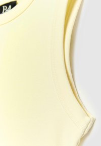 Haut sans manches jaune clair avec encolure ronde et coutures visibles sur fond blanc uni.
