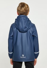 Jūras zila ūdensnecaurlaidīga jaka ar kapuci, elastīgām piedurknēm un baltām akcentiem. Logo izvietots aizmugurē tuvumā apakšmalai. Gluda, spīdīga tekstūra.