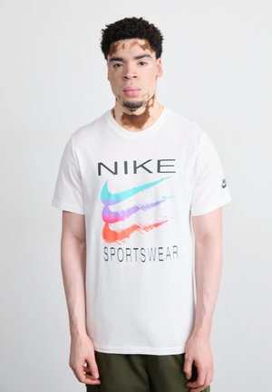 Tricou alb din bumbac, cu un logo Nike colorat, având accente de albastru, roz și roșu. Textul "SPORTSWEAR" este afișat în negru, cu litere îngroșate, sub logo.