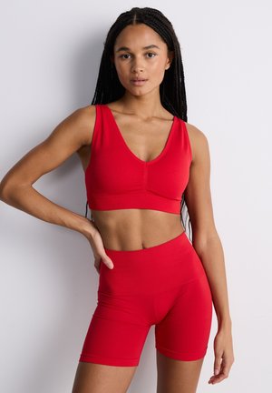 Set composto da reggiseno sportivo rosso e pantaloncini a vita alta, con texture a coste, design a scollo a V, silhouette aderente, spalline larghe e fascia della vita liscia.
