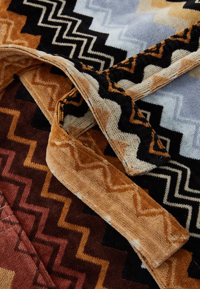Tessuto a fantasia multicolore con motivi a zigzag nelle tonalità di arancione, marrone, nero e azzurro chiaro; tessuto morbido e texturizzato.