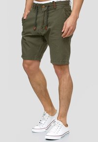 Khaki korte broek van katoenmix, met een elastische tailleband met trekkoord, twee zijzakken en opgerolde zoompjes, gecombineerd met witte canvas sneakers.
