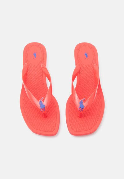 Ζευγάρι κοραλλί σαγιονάρες με υφασμένους πάτους και μοβ λογότυπο αλόγου στα λουριά, παρουσιάζονται σε ουδέτερο φόντο.