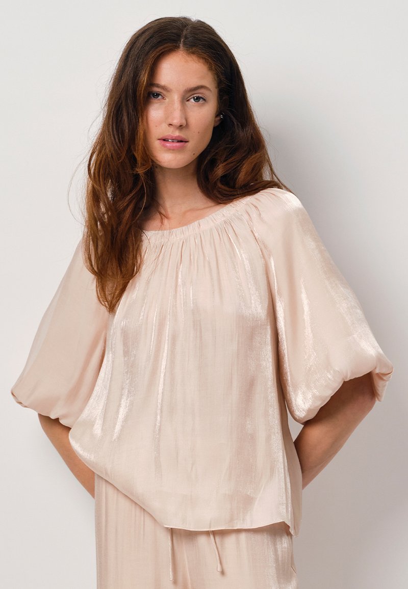 Vloeiende top met korte mouwen van zacht beige stof met een glanzende afwerking. Geraffineerde halslijn met een ontspannen pasvorm en elastische mouwen.