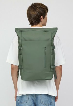 Grüner Rolltop-Rucksack mit einem eleganten Design, aus strapazierfähigem Material gefertigt. Verfügt über Seitenträger und eine mit Reißverschluss gesicherte Vordertasche. Markenlogo sichtbar.