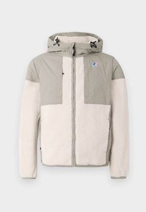 Giacca foderata in pile con una combinazione di colori grigio chiaro e crema, chiusura con zip, cappuccio e due tasche sul petto con un'accenno di logo.