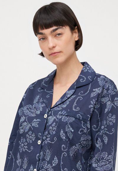 Navy blue floral print button-up shirt with a collar, featuring white buttons and a chest pocket, made from lightweight fabric with a smooth texture.