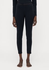 Leggings navy avec une taille haute élastique portant la marque "PeakPerformance", fabriqués dans un tissu lisse, longueur cheville avec une coupe ajustée.