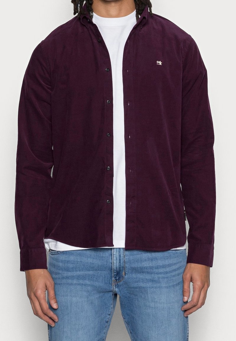 Camicia a maniche lunghe color bordeaux in tessuto corduroy, con colletto, chiusura a bottoni e piccolo logo sul petto.