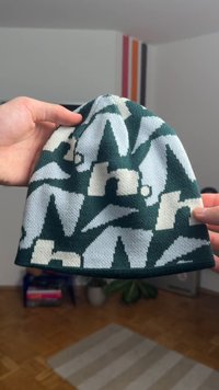 Gebreide muts met een groen, wit en crèmekleurig geometrisch patroon met abstracte vormen. Gemaakt van zachte stof, licht gestructureerd ontwerp.