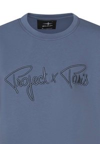 T-shirt en coton bleu arborant un design brodé bien en vue avec le texte "Project x Paris" dans un style cursif sur le devant.