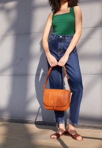 Grønt ribbet tanktop, højhvide blå denim jeans, brunt læder crossover taske og brune vævede sandaler. Struktureret og afslappet stil.