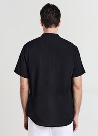 Chemise noire à manches courtes en tissu texturé, avec un col à revers et un ourlet droit, conçue pour une coupe décontractée.