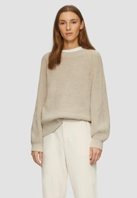 Beige gebreide trui met een losse pasvorm, geribbelde structuur en iets verlaagde schouders. Draag deze met crèmekleurige, wijdvallende broeken.