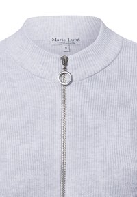 Lichtgrijze cardigan met een ribbelstructuur, voorzien van een hoge kraag en een zilveren rits met een ronde trekker. Etiket zegt "Marie Lund, Kopenhagen."