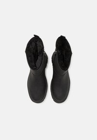 Botas negras hasta el tobillo con un exterior de cuero suave, un forro de suave piel sintética negra y cremalleras laterales para un fácil acceso. Diseño de puntera redonda.