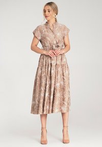 Beiges, floral Midi-Kleid mit kurzen Ärmeln, Bindegürtel und mehrere Lagen im Rock; es hat weiße Blumenstickereien und einen leichten Stoff.