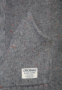 Szary dzianinowy sweter z fakturowanym wzorem z czerwonymi i niebieskimi plamkami oraz metką z napisem „ORIGINALS by JACK & JONES.”