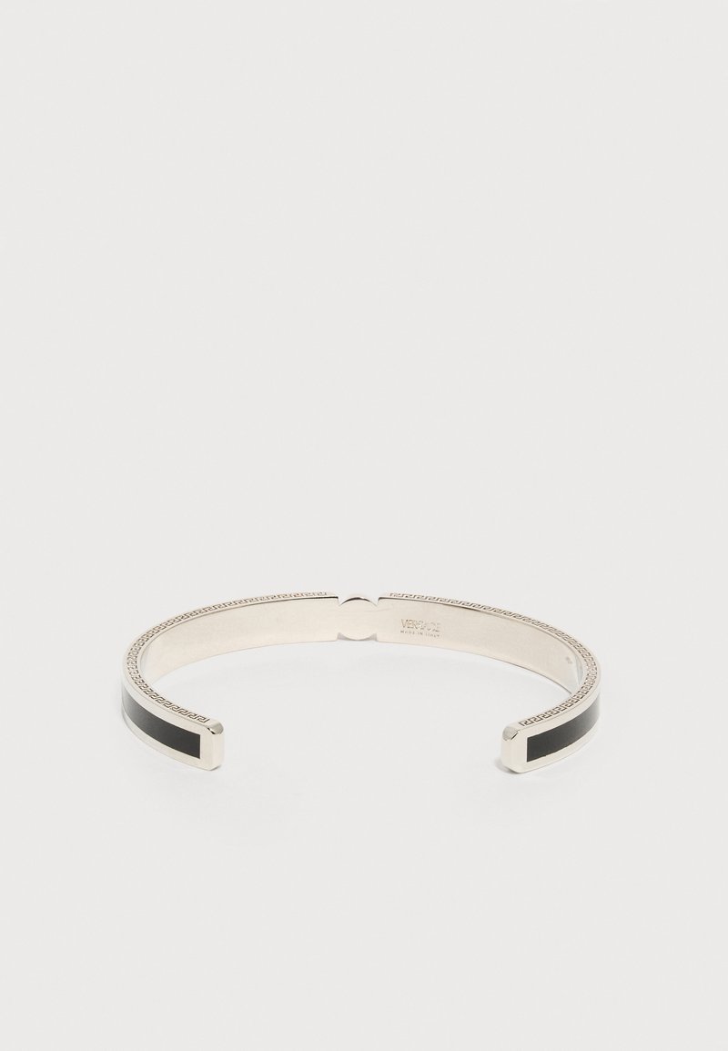 Bracelet manchette ouvert en ton argent avec incrustations noires et motif clé grec gravé le long des bords, marqué à l'intérieur "Versace Made in Italy".