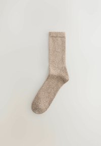 Beige gerippte Socke aus einem strukturierten Material. Verfügt über ein hohes Knöcheldesign mit leicht abgerundetem Zehenbereich und dezenten Nähdetails.