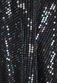 Fekete szövet, amelyet flitterek borítanak, irizáló kör alakú mintákkal. A felület fényesnek tűnik, és csillogó hatással rendelkezik, ahogy a fény különböző szögből éri.