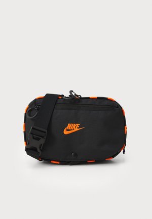 Mustakosinen olkalaukku, jossa on oranssit yksityiskohdat. Laukussa on etuvetoketju, säädettävä hihna ja Nike-logo edessä.