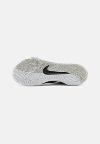 Biela atletická podrážka so štruktúrovanými čiernymi akcentmi, s cik-cak vzorom a kruhovými detailmi pre trakciu. Prítomné výrazné logo Nike.