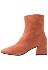 Nubuck enkellaarsjes in koraal met een spitse neus en een blokhak van 5 cm. Gladde textuur met minimale branding aan de buitenkant.