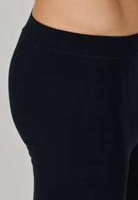 Schwarze Leggings aus dehnbarem Stoff, mit einer glatten Textur und einem elastischen Bund, in einer taillierten Form und ohne sichtbare Muster.