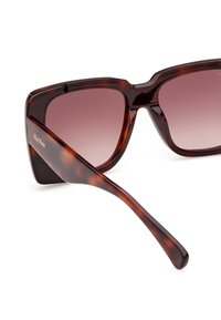 Gafas de sol de carey con montura cuadrada, lentes graduales de oscuros a claros y un acabado suave y brillante en las varillas.