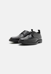 Pantofi negri din piele cu un finisaj lucios, vârf rotund și design cu șireturi. Au o talpă robustă din cauciuc negru și un stil minimalist.