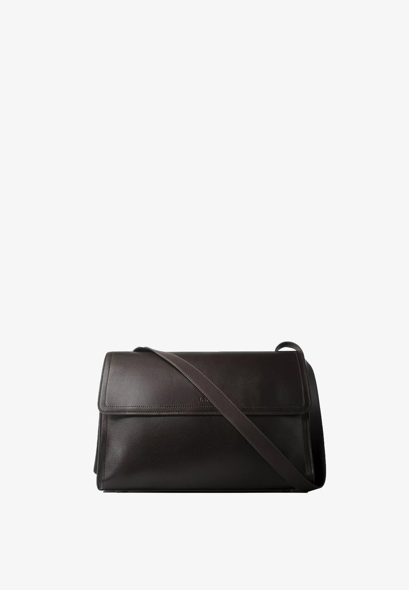 Sac à épaule en cuir noir avec rabat et une sangle réglable placée en diagonale à l'avant.