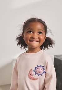 Light pink sweatshirt featuring appliqué designs of a smiling sun and crescent moon. Soft texture with ribbed neckline and relaxed fit.
