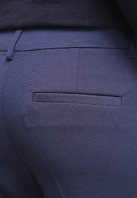 Marina blå byxor i strukturerad tygkvalitet, med en elegant design och en enda bakficka. Snygga sömmar längs kanterna.