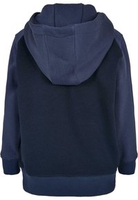 Námořnicky modrá mikina s kapucí s jemnou texturou, elastickými manžetami a uvolněným střihem. Zadní pohled zvýrazňuje design kapuce a kontrast látek.