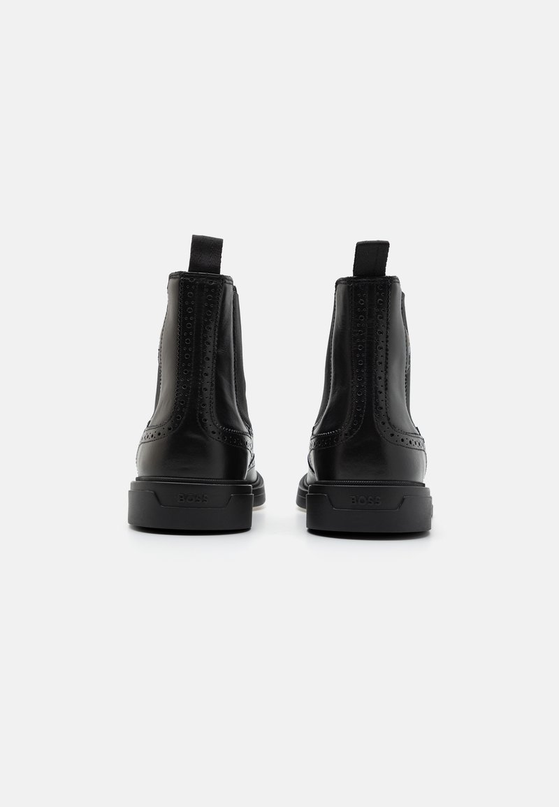 Schwarze Lederknöchelstiefel mit glatter Oberfläche, elastischen Seiteneinsätzen und einem strukturierten Akzent entlang des Schafts. Mit einer robusten Gummisohle ausgestattet.
