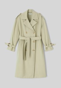 Manteau trench double-breasted beige clair avec des revers larges, une ceinture à la taille, des épaulettes et des sangles à boucle aux poignets, posé à plat.