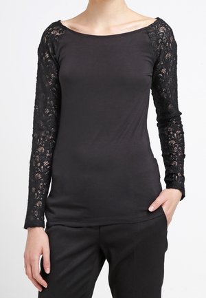 Maglietta nera a manica lunga con dettagli in pizzo sulle maniche, scollatura a barchetta e silhouette aderente. Tessuto morbido e elasticizzato con una texture liscia.