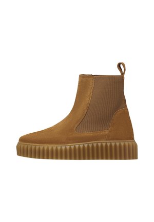 Brown suede ankle boot with elastic side panel and textured rubber sole, featuring a pull tab at the back for easy wear.