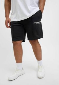 Shorts en coton noirs avec une taille élastique et des poches latérales. Logo "Originals Studio" imprimé en blanc sur la cuisse gauche.