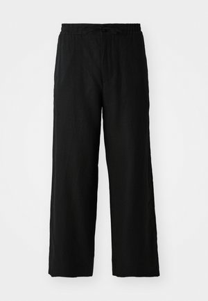 Pantalon large noir en tissu léger, avec une taille élastique dotée d'un cordon de serrage et sans poches visibles ni motifs.