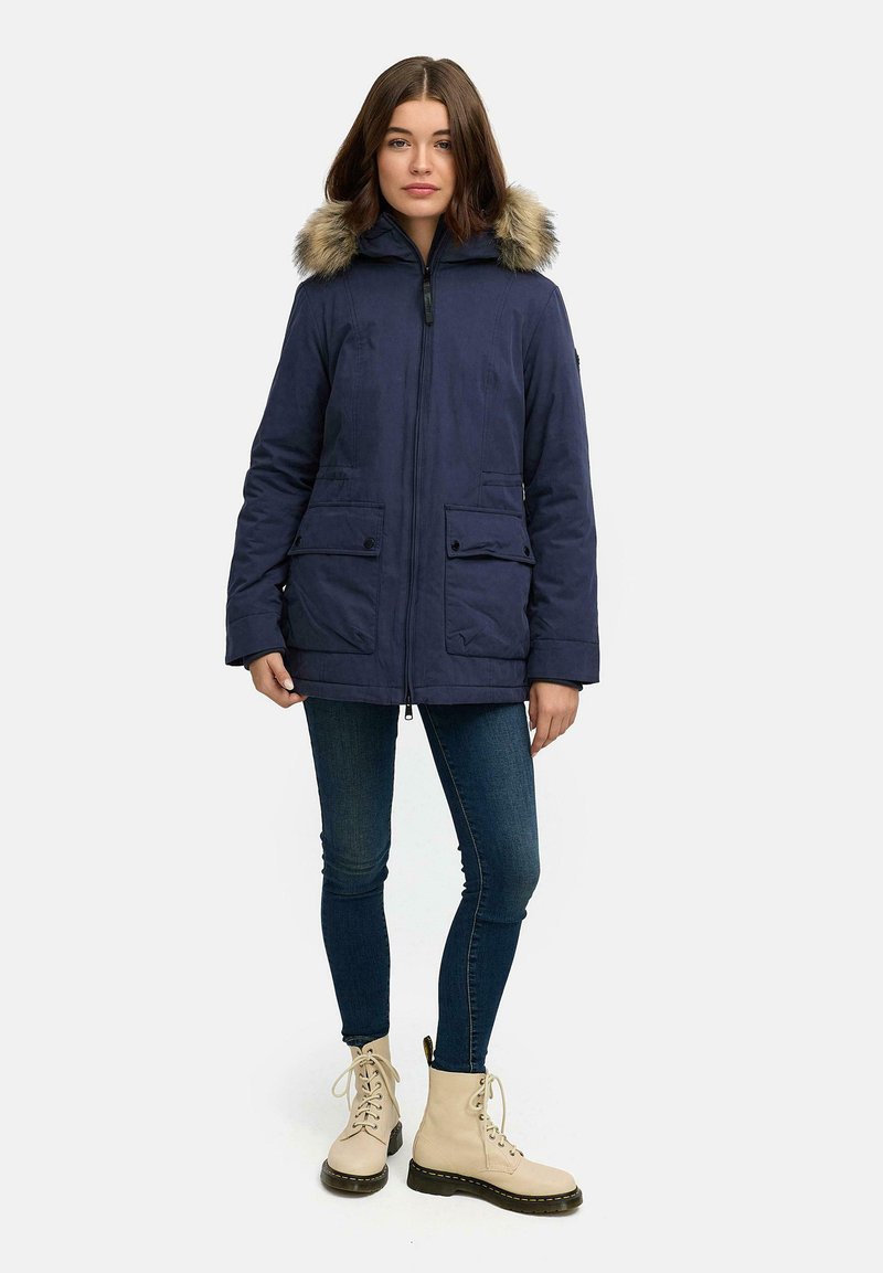 Tumesinine parka jakk, millel on karvane kapuuts, kaks eesmist taskut ja lukuga sulgus. Täiendavad detailid hõlmavad pehmet tekstuuri ja sooja disaini.