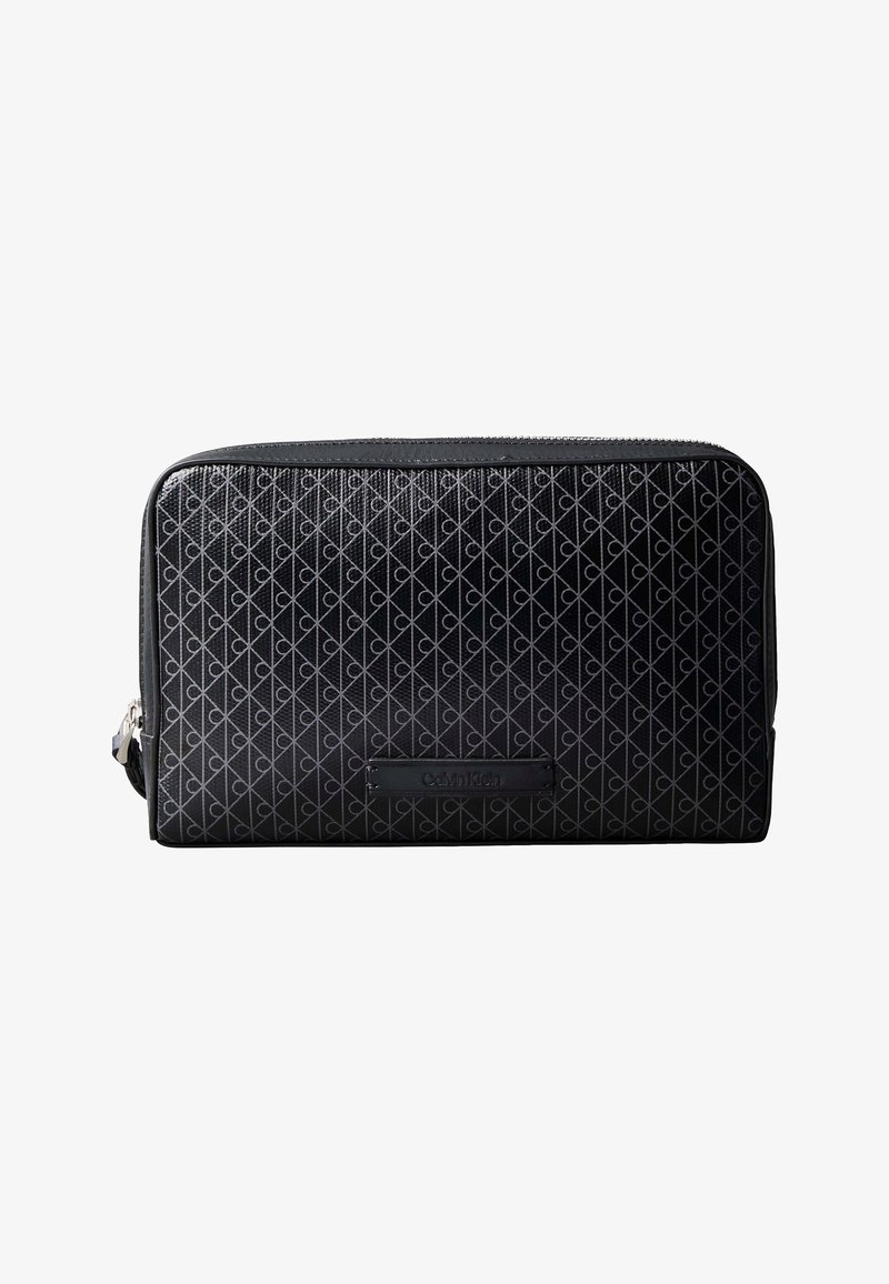 Trousse de toilette rectangulaire noire avec un motif géométrique et une fermeture éclair sur le dessus, avec un petit patch logo Calvin Klein à l'avant.