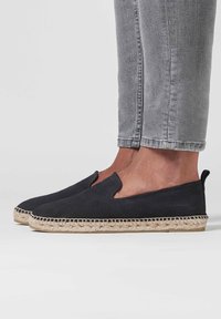 Espadrilles en suède noir avec des côtés découpés et une semelle en jute tressé. Présentent une texture lisse et un design minimaliste.
