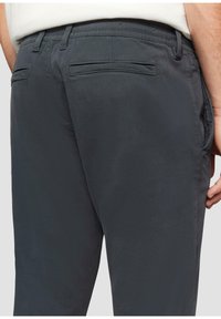 Grijze, gestructureerde broek met elastische tailleband en twee achterzakken. Heeft een eenvoudig, schoon ontwerp zonder zichtbare hardware.