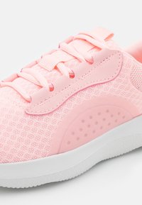 Zapatilla deportiva rosa con parte superior de malla, acentos texturizados, cordones planos y una suela de goma blanca con un patrón circular.