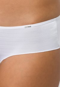 Weiße Baumwoll-Hipster-Unterwäsche mit glatter Textur und einem dezenten Markenetikett am Bund. Nahaufnahme der Details des Stoffes.