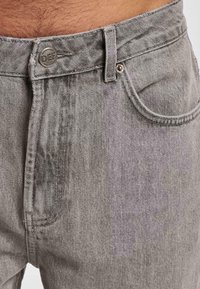 Grijze denim jeans met een klassieke vijf-vakken ontwerp, een metalen knoopsluiting en een gestructureerde afwerking. De stof vertoont subtiele vervaging.