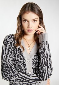 Strikket cardigan i grå og sort med et mønsterdesign, V-hals, ribbede manchetter og store knapper foran.